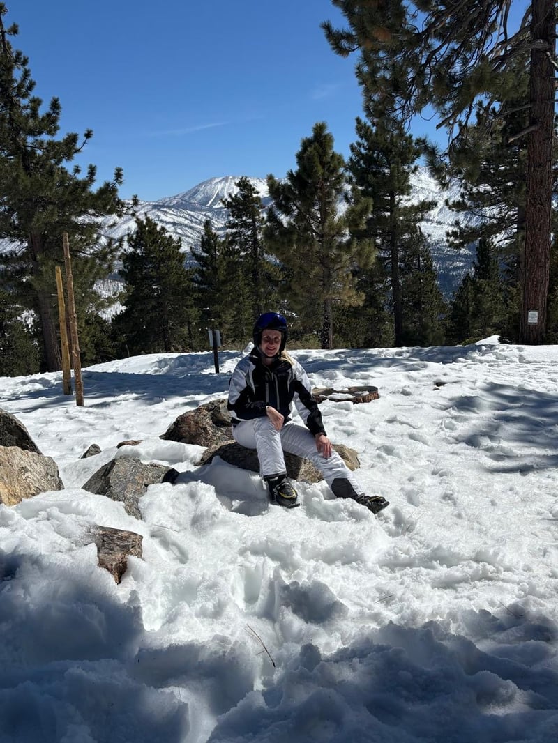 Miriam sentada en la nieve con montañas nevadas al fondo