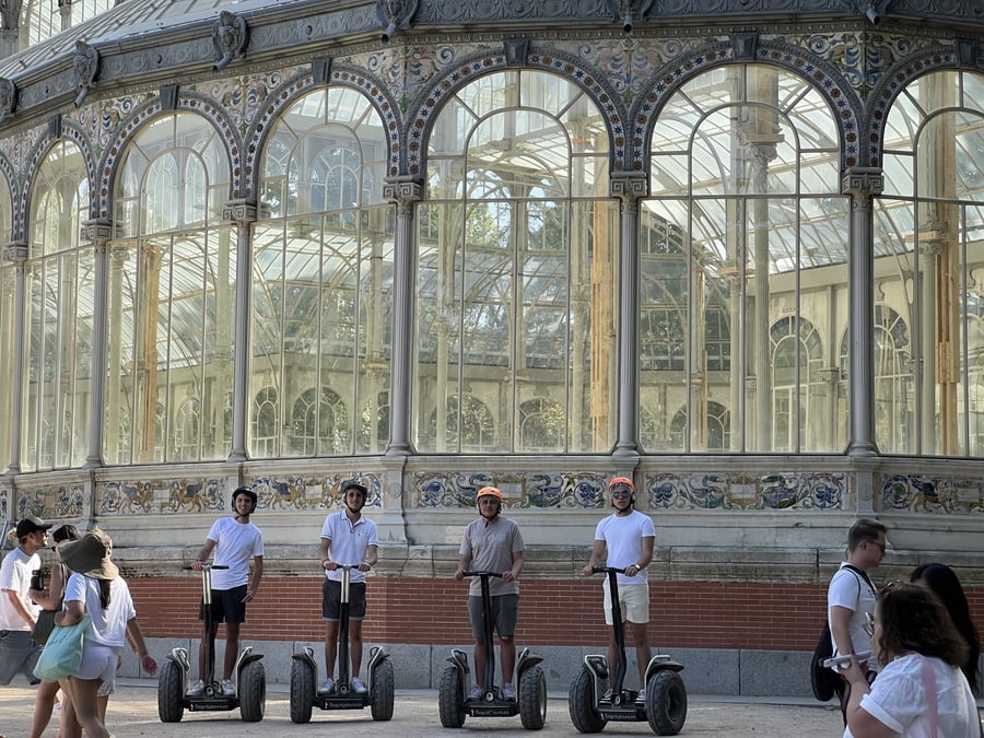 Grupo de jóvenes realizando un tour en Segway frente al Palacio de Cristal en Madrid.
